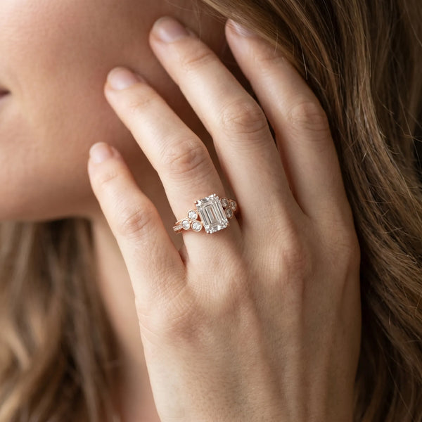 Rose gold Emerald Cut Diamond Engagement Ring with Bezel Set Round Side Stones and Prong Setting