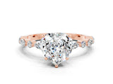Rose gold Heart Cut Moissanite Solitaire with Side Stones on a Pavé Band and Four-Prong Setting