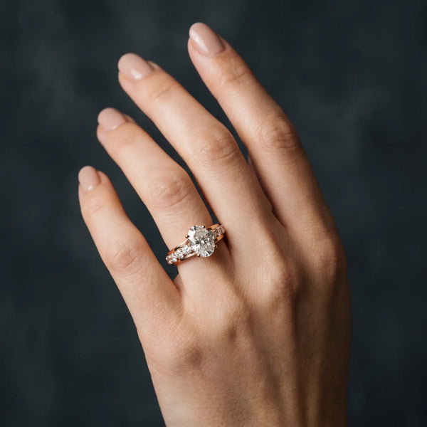 Rose gold Oval Brilliant Solitaire with Side Stones on a Pave Band and Four-Prong Setting