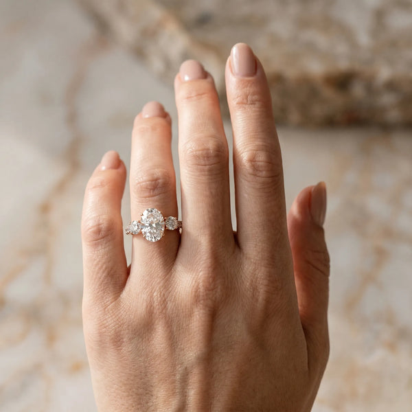 Rose gold Oval Cut Diamond Three-Stone Ring with Round Side Stones and Pavé Band