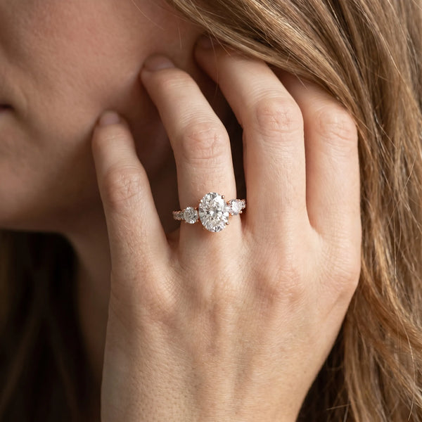 Rose gold Oval Cut Diamond Three-Stone Ring with Round Side Stones and Pavé Band