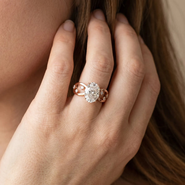 Rose gold Oval Cut Solitaire Diamond with Side Stones on Criss-Cross Band and Four-Prong Setting