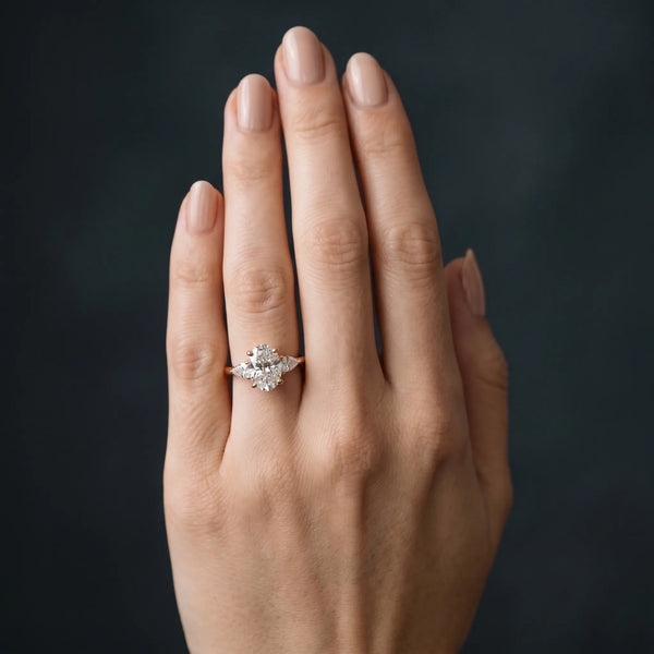 Rose gold Oval Cut Three-Stone Diamond Ring with Pear Side Stones on a Classic Solitaire Band with Prong Setting