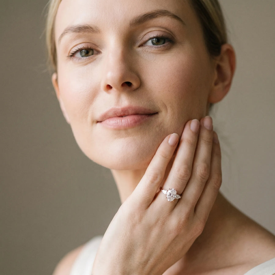 Rose gold Oval Cut Three-Stone Diamond Ring with Pear Side Stones on a Classic Solitaire Band with Prong Setting