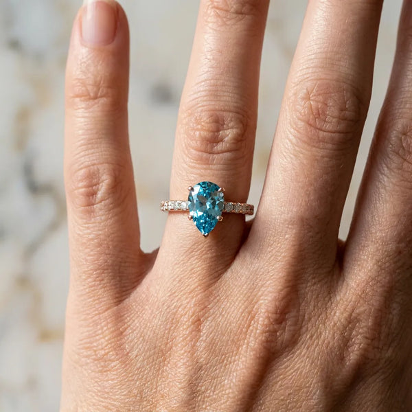 Rose gold Pear Cut Blue Topaz Solitaire Ring with Round Pavé Band and Four-Prong Setting