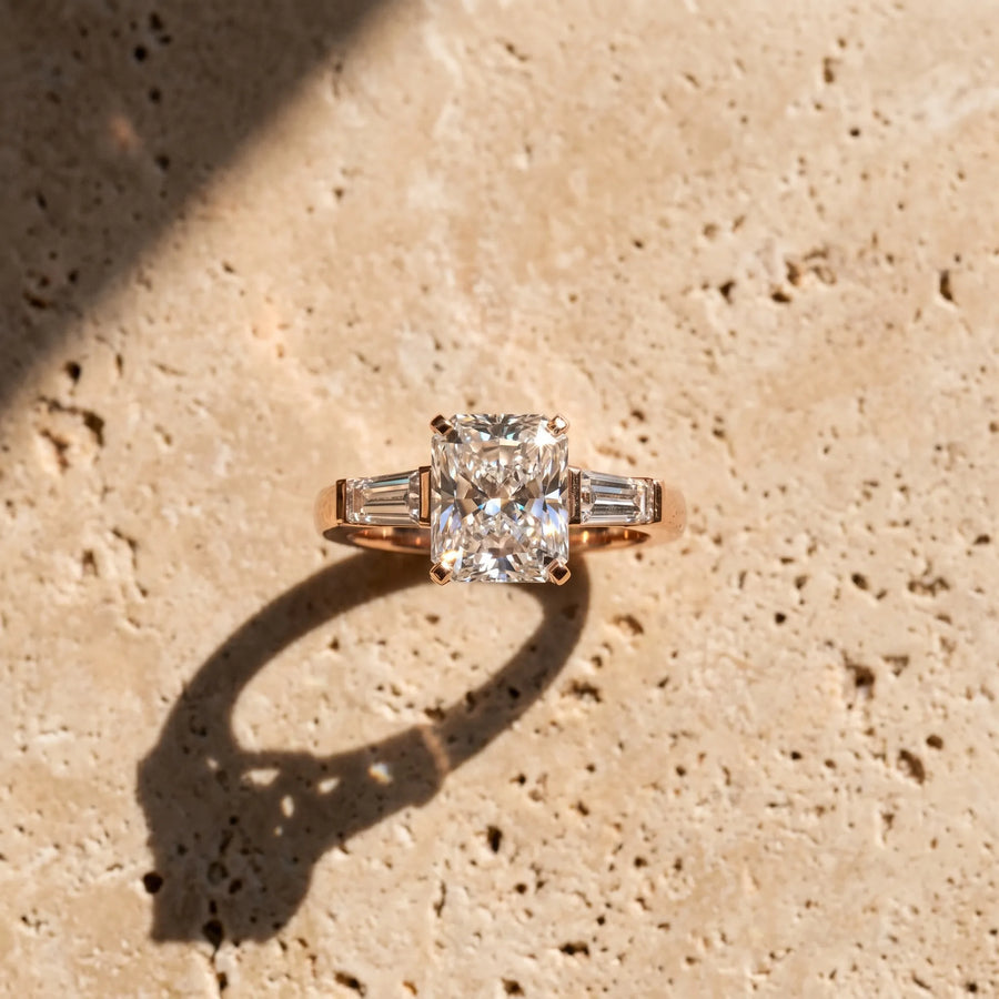 Rose gold Radiant Solitaire with Tapered Baguette Side Stones on a Classic Band with Four-Prong Setting