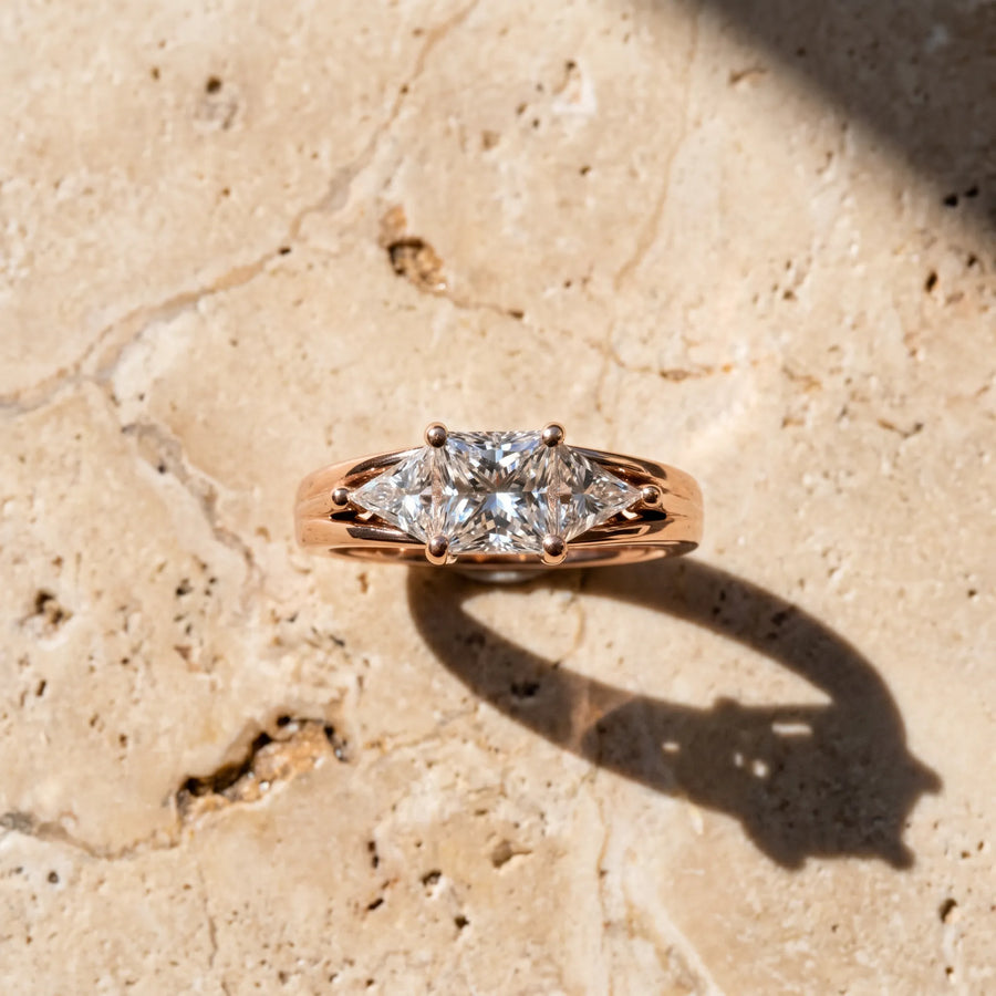 Rose gold Three-Stone Princess Cut Diamond Ring with Trillion Side Stones on a Split Shank Band