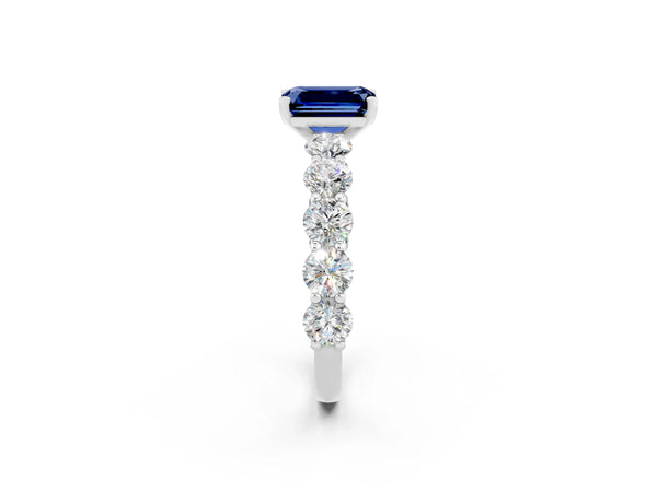 White gold Emerald Cut Blue Sapphire Prong Setting with Side Stones on a Pave Band