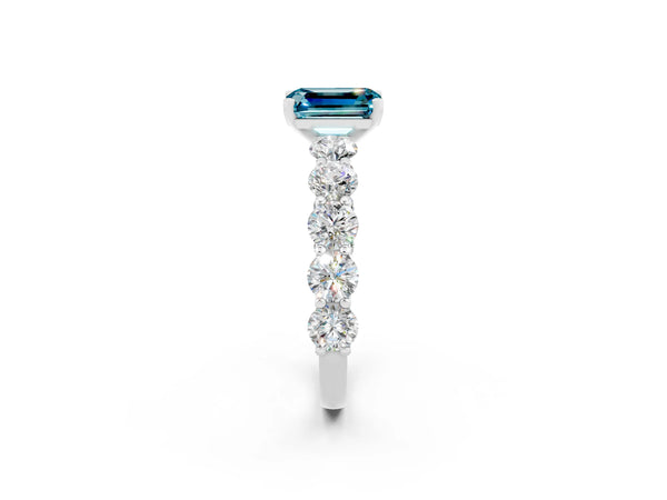 Platinum Emerald Cut Blue Topaz Prong Setting with Side Stones on a Pave Band