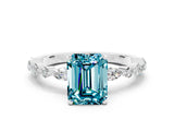 White gold Emerald Cut Blue Topaz Solitaire with Side Stones on a Pavé Band and Four-Prong Setting