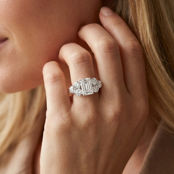 White gold Emerald Cut Diamond Cluster Ring with Round Accent Stones and Prong Setting on a Classic Band