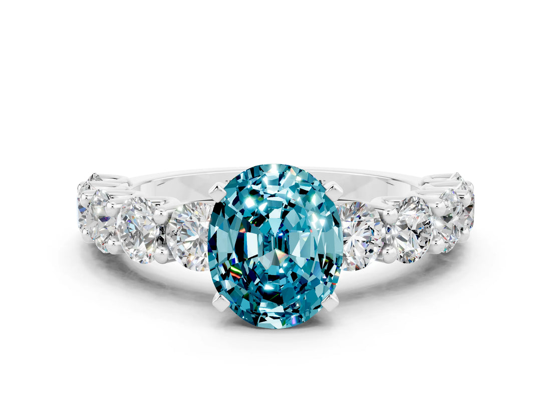White gold Oval Cut Blue Topaz Prong Setting with Side Stones on a Pave Band