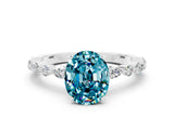White gold Oval Cut Blue Topaz Solitaire with Side Stones on a Pavé Band and Four-Prong Setting