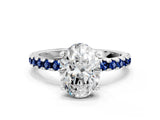 White gold Oval Cut Diamond Solitaire Ring with Round with Blue Sapphire side stone Pavé Band and Four-Prong Setting