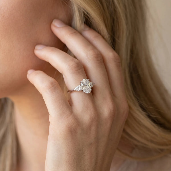 White gold Oval Cut Three-Stone Diamond Ring with Pear Side Stones on a Classic Solitaire Band with Prong Setting