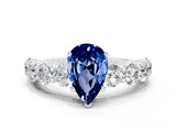 White gold Pear Cut Blue Sapphire Prong Setting with Side Stones on a Pave Band
