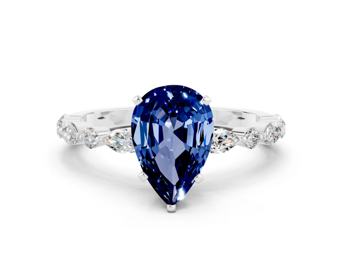 White gold Pear Cut Blue Sapphire Solitaire with Side Stones on a Pavé Band and Four-Prong Setting
