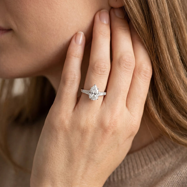 White gold Pear Cut Diamond Ring with Baguette Side Stones, Channel Set Band, and Four-Prong Setting