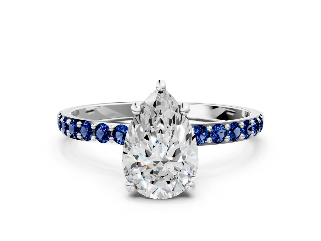 White gold Pear Cut Diamond Solitaire Ring with Round with Blue Sapphire side stone Pavé Band and Prong Setting