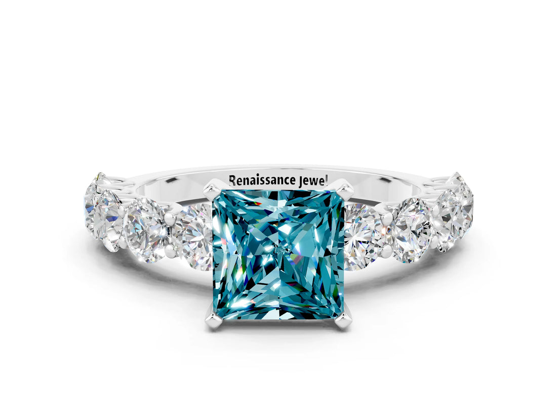 White gold Princess Cut Blue Topaz Prong Setting with Side Stones on a Pave Band