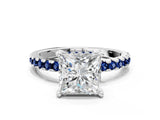 White gold Princess Cut Diamond Solitaire Ring with Round with Blue Sapphire side stone Pavé Band and Four-Prong Setting