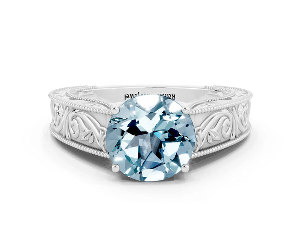Platinum Round Cut Aquamarine Solitaire Ring with Engraved Band and Four-Prong Setting