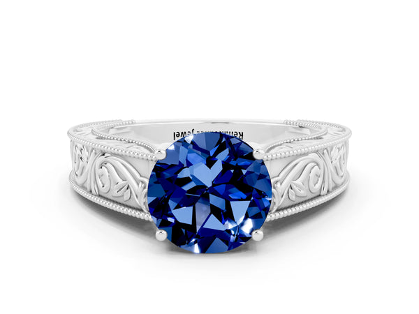 Platinum Round Cut Blue Sapphire Solitaire Ring with Engraved Band and Four-Prong Setting