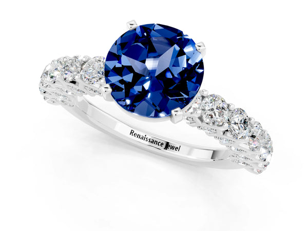 Platinum Round Cut Blue Sapphire Solitaire Ring with Shared Prong Pavé Band and Four-Prong Setting