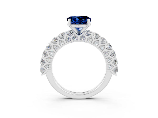 Platinum Round Cut Blue Sapphire Solitaire Ring with Shared Prong Pavé Band and Four-Prong Setting