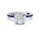 White gold Round Cut Diamond Solitaire Ring with Round with Blue Sapphire side stone Pavé Band and Four-Prong Setting