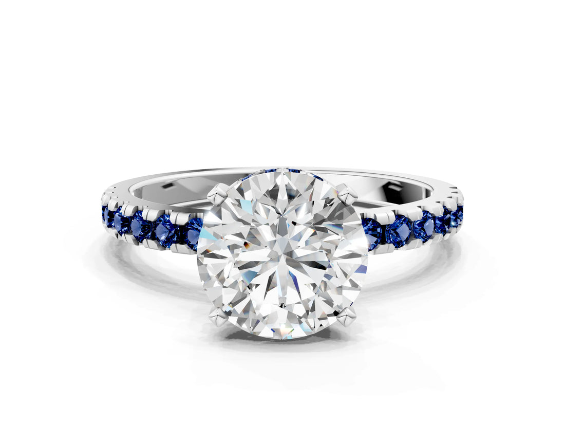White gold Round Cut Diamond Solitaire Ring with Round with Blue Sapphire side stone Pavé Band and Four-Prong Setting