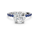 White gold Round Cut Diamond Solitaire Ring with Round with Blue Sapphire side stone Pavé Band and Prong Setting
