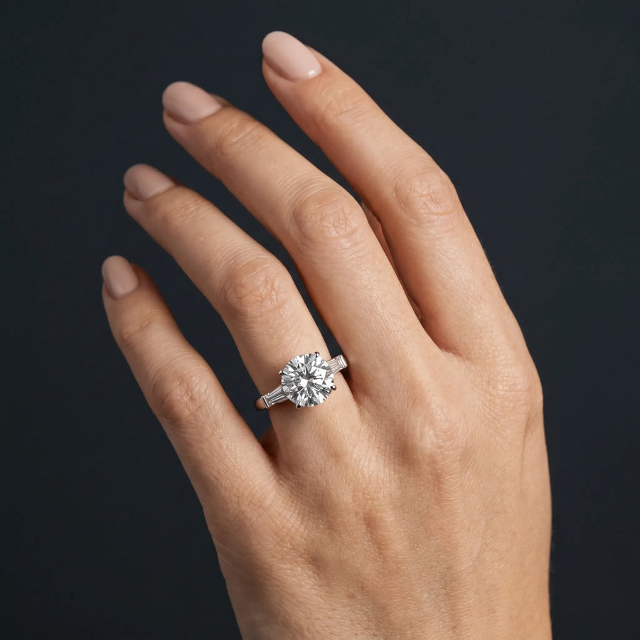 White gold Round Cut Diamond Solitaire Ring with Tapered Baguette Accents and Four-Prong Setting
