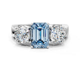 White gold Three-Stone Fancy Blue Emerald Cut Diamond Ring with Round Side Stones, Classic Band, and Four-Prong Setting