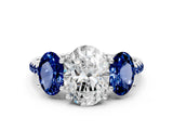 White gold Three-Stone Oval Cut Diamond Ring with Round with Blue Sapphire side stone Pavé Band and Prong Setting