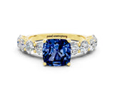 Yellow gold Cushion Cut Blue Sapphire Prong Setting with Side Stones on a Pave Band
