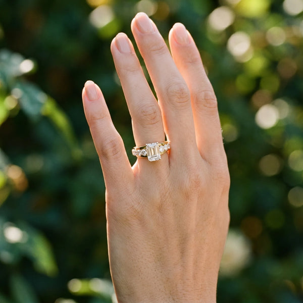 Yellow gold Emerald Brilliant Solitaire with Side Stones on a Pave Band and Four-Prong Setting