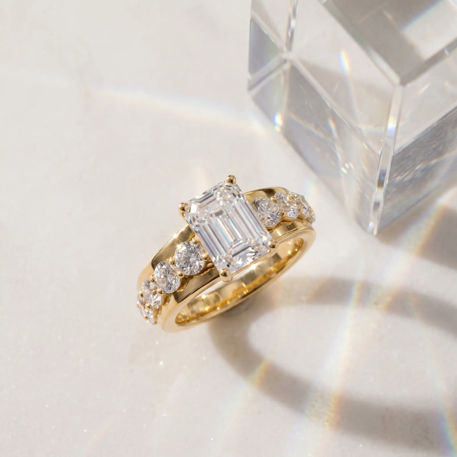 Yellow gold Emerald Brilliant Solitaire with Side Stones on a Pave Band and Four-Prong Setting