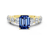 Yellow gold Emerald Cut Blue Sapphire Prong Setting with Side Stones on a Pave Band