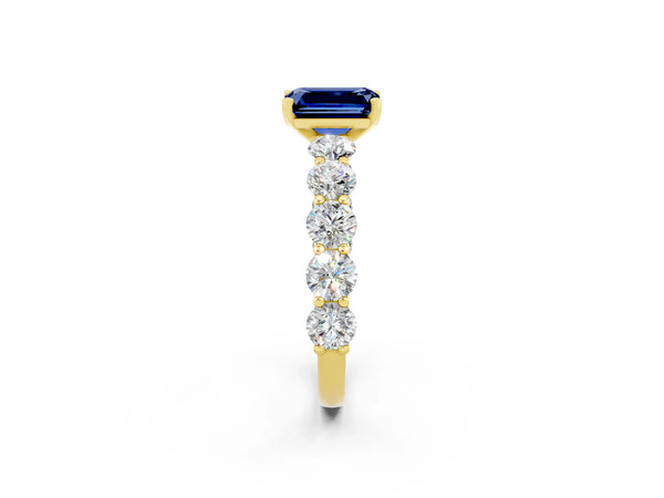 Yellow gold Emerald Cut Blue Sapphire Prong Setting with Side Stones on a Pave Band