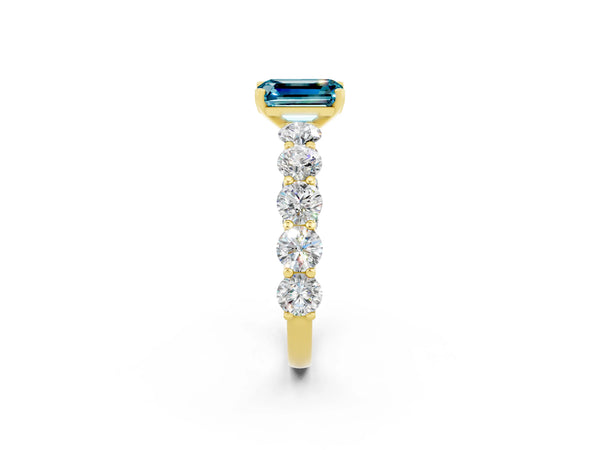 Yellow gold Emerald Cut Blue Topaz Prong Setting with Side Stones on a Pave Band