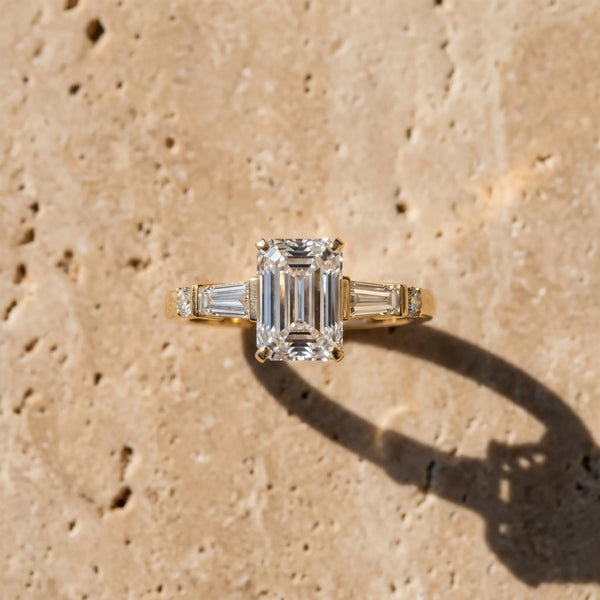 Yellow gold Emerald Cut Diamond Ring with Baguette Side Stones, Channel Set Band, and Four-Prong Setting