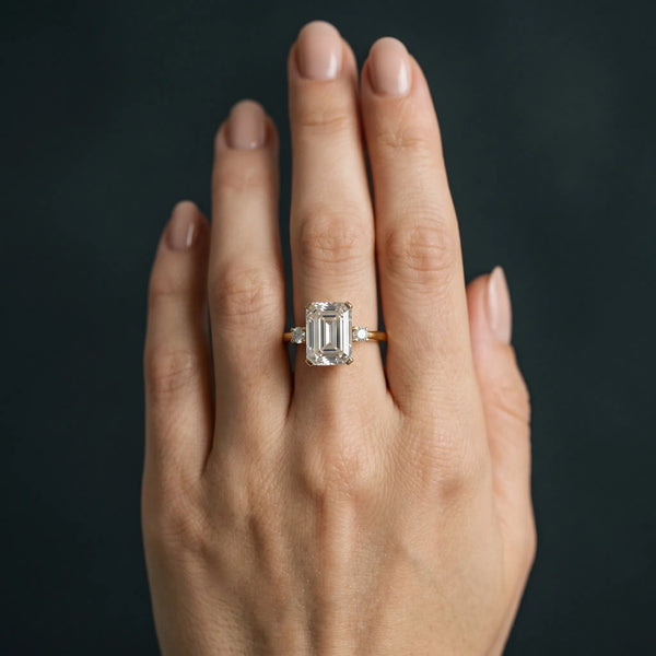 Yellow gold Emerald Cut Three-Stone Solitaire Ring with Round Accent Diamonds and Four-Prong Setting