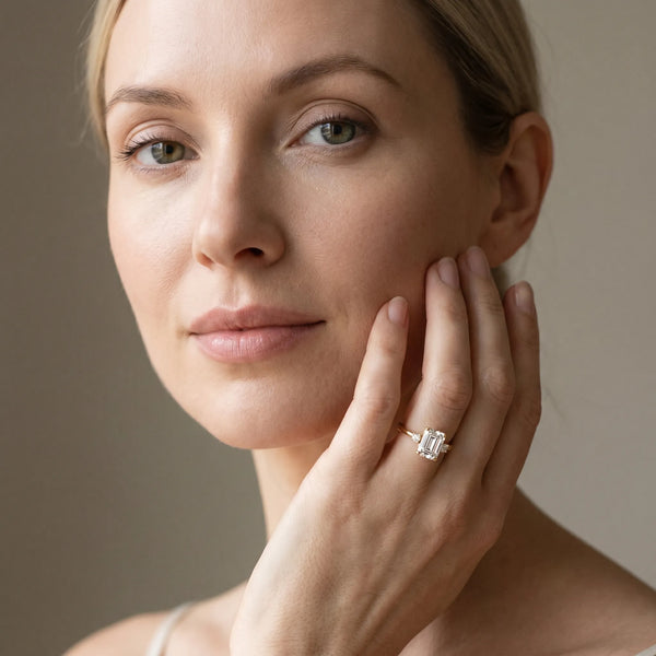Yellow gold Emerald Cut Three-Stone Solitaire Ring with Round Accent Diamonds and Four-Prong Setting