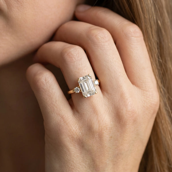 Yellow gold Emerald Cut Three-Stone Solitaire Ring with Round Accent Diamonds and Four-Prong Setting
