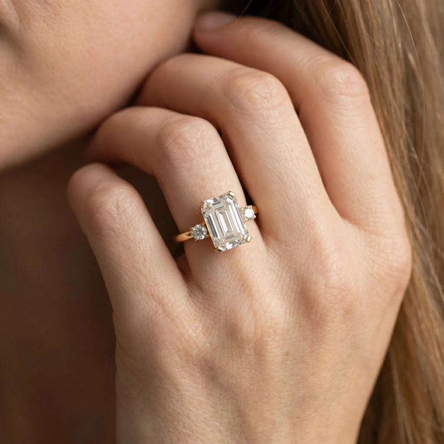 Yellow gold Emerald Cut Three-Stone Solitaire Ring with Round Accent Diamonds and Four-Prong Setting