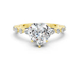Yellow gold Heart Cut Moissanite Solitaire with Side Stones on a Pavé Band and Four-Prong Setting