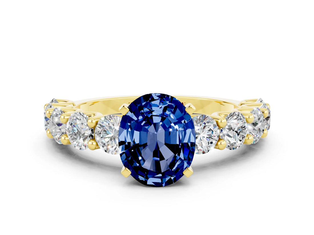 Yellow gold Oval Cut Blue Sapphire Prong Setting with Side Stones on a Pave Band