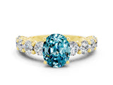 Yellow gold Oval Cut Blue Topaz Prong Setting with Side Stones on a Pave Band