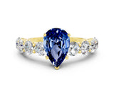 Yellow gold Pear Cut Blue Sapphire Prong Setting with Side Stones on a Pave Band